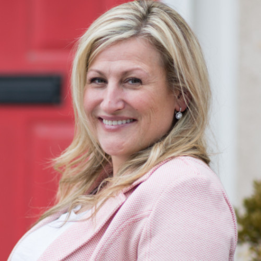 Photo of Rachel Oliver, a smiling white woman with blond hair wearing a pink jacket