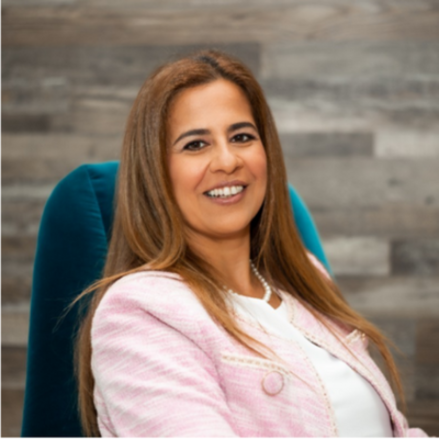 Photo of Dalia Barsoum, a smiling Middle Eastern woman wearing pink and sitting in a chair